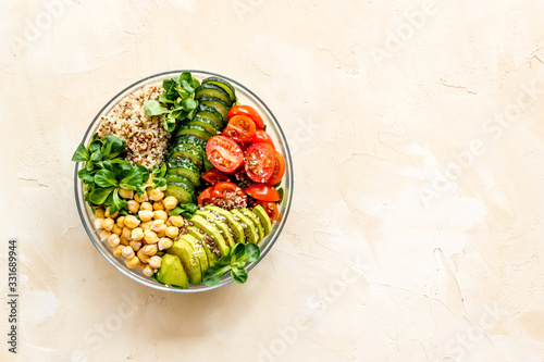 Healhty vegan lunch bowl. Avocado, quinoa, sweet potato, tomato, spinach and chickpeas vegetables salad on brown table. Top view