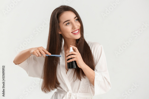 Beautiful young woman with cosmetics for hair on white background