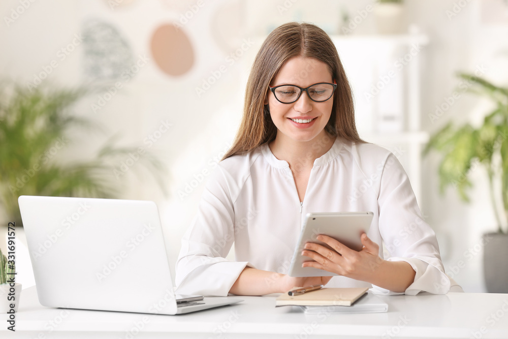 Portrait of beautiful young businesswoman with tablet computer at table in office Portrait of beautiful young businesswoman with tablet computer at table in office