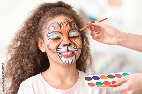 Woman painting face of cute...