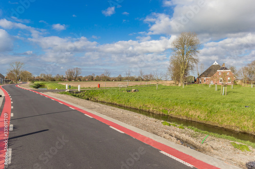 Winding road and historic farm near Thesinge, Groningen, Netherlands