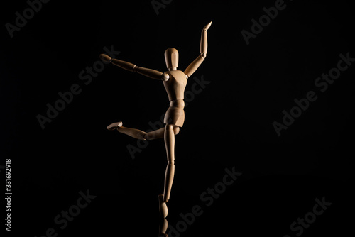 Wooden doll imitating dancing on black