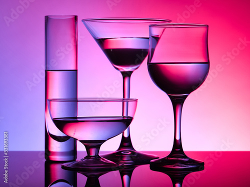 Different glass goblets on a red and purple background. Beautiful still life
