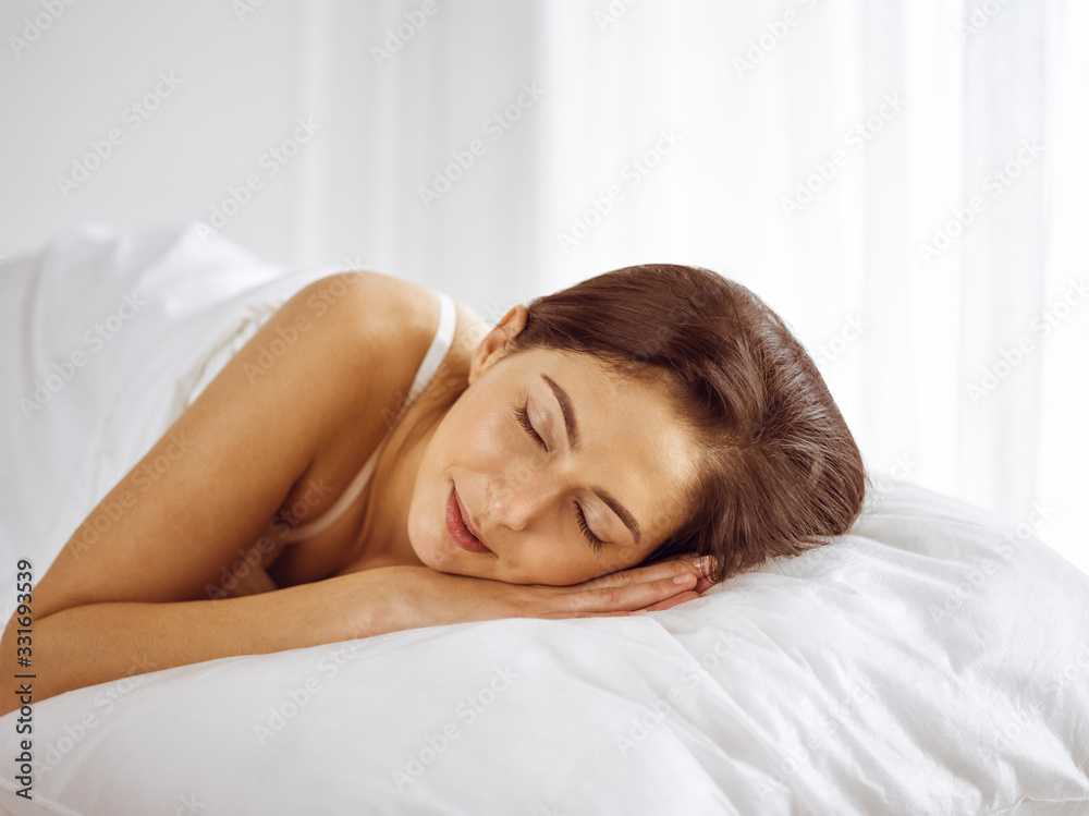 Beautiful young brunette woman sleeping while lying in bed comfortably and blissfully. Good morning concept Beautiful young brunette woman sleeping while lying in bed comfortably and blissfully. Good morning concept