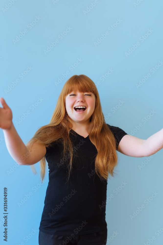 birthday, valentines day concept. Happy red-haired girl holding a bouquet of gold-colored balloons on a blue background, the girl is happy