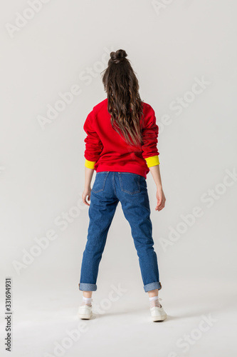 Girl in jeans and red sweatshirt standing back to the camera