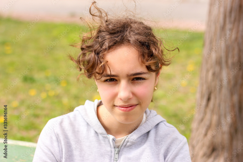 Portrait of calm curly teenager girl outside at the park