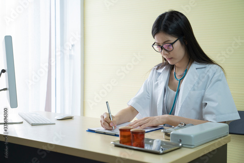 Asian young female doctor is working notes while in his office.