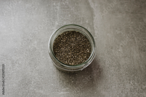 Chia seeds in glass jar on grey background. Place for text. superfood concept