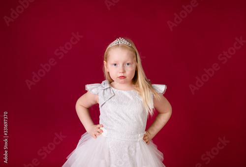 Little blonde girl in a christmas and new year green costume having fun and sending kisses on red background. Space for text. Dreams come true Merry Christmas