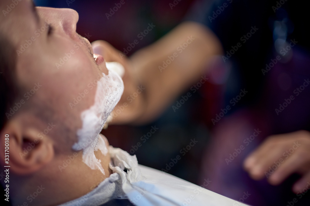 Obraz premium Shaving process of beards in Barbershop. Master makes the client shave his beard with vintage straight razor.