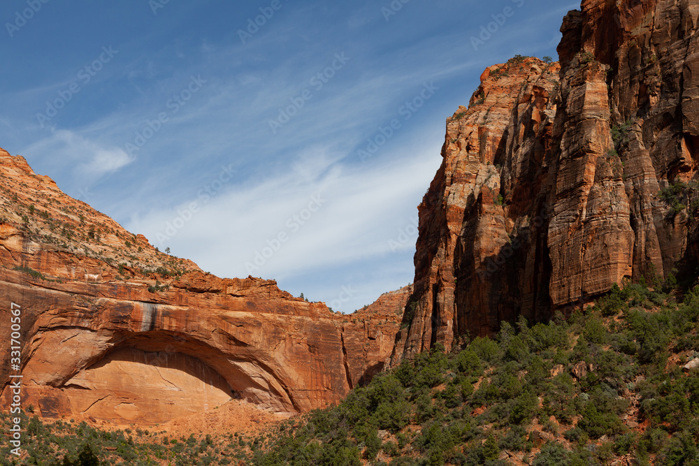Amazing red rock wall inside Zion Park, with a natural cave in the shape of an arch eroded by natural agents Amazing red rock wall inside Zion Park, with a natural cave in the shape of an arch eroded by natural agents