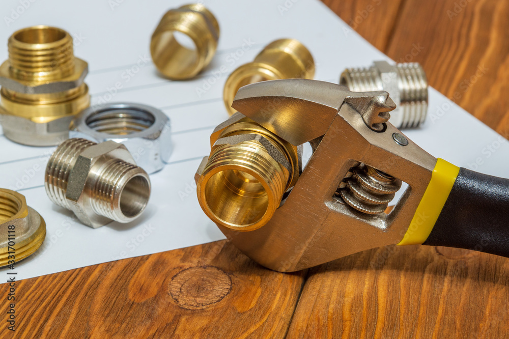 Many plumbing spare parts and adjustable spanner closeup on the sheet for notes and preparation of a repair plan Many plumbing spare parts and adjustable spanner closeup on the sheet for notes and preparation of a repair plan