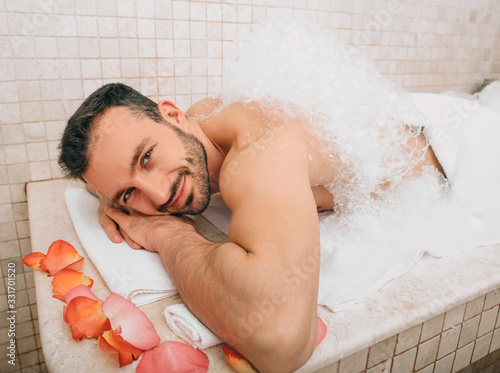 Oriental man looking into the frame during a foamy massage in a hammam . Traditional turkish bath photo