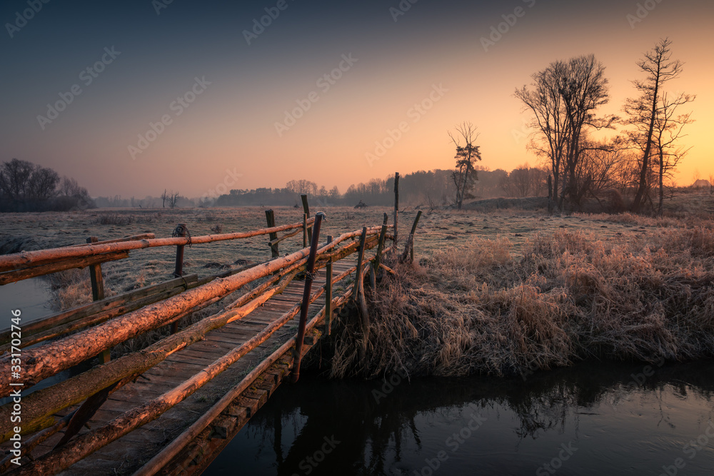 Wooden bridge over the Jeziorka river at sunrise near Piaseczno, Poland
