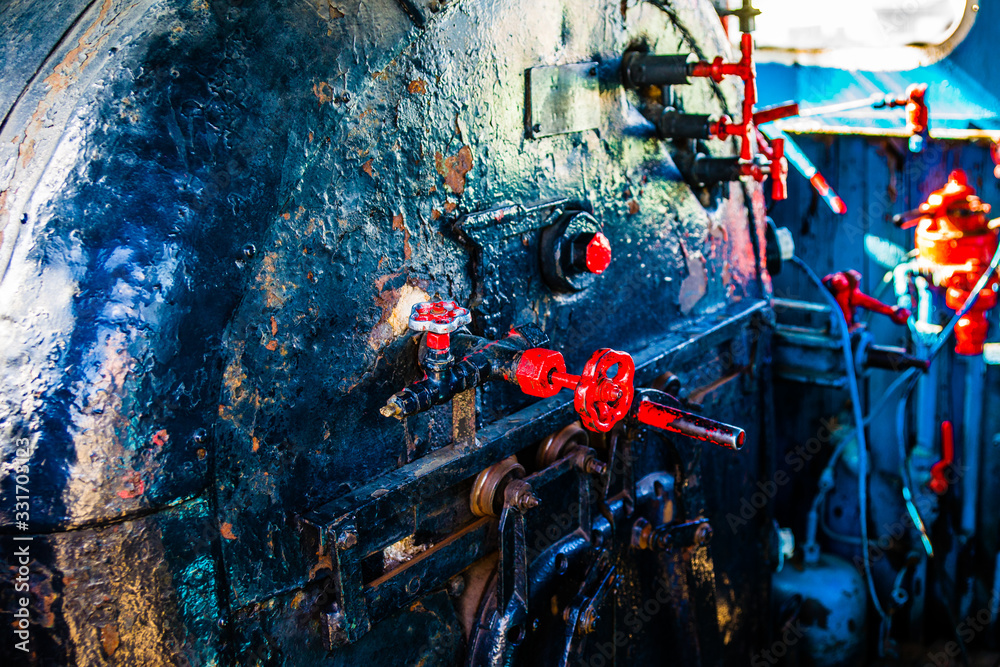Inside the engineer's cabin of the vintage steam engine locomotive. Grunge boiler and furnace, red valves. Peeled off blue paint. The history of railway transport.