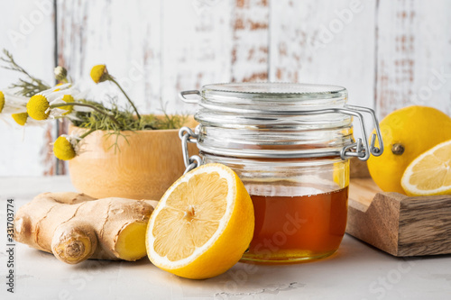Alternative medicine, natural home remedy for cold and flu. Glass jar with honey, ginger, lemon and camomile