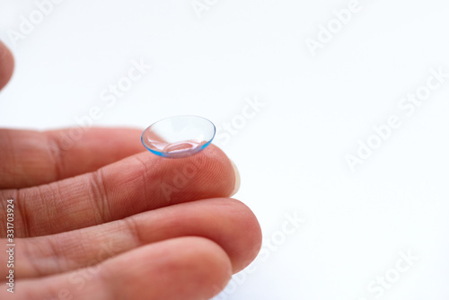 Female finger with contact lens on white background. Soft focus. Macro. Ophthalmology and health concept