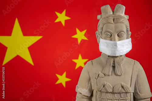 Terracotta warrior with mask and Chinese flag in the background. Coronavirus concept