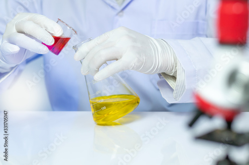 Close up of a scientist holding a beaker for mixing liquid In the lab, Concept of research and medical science.