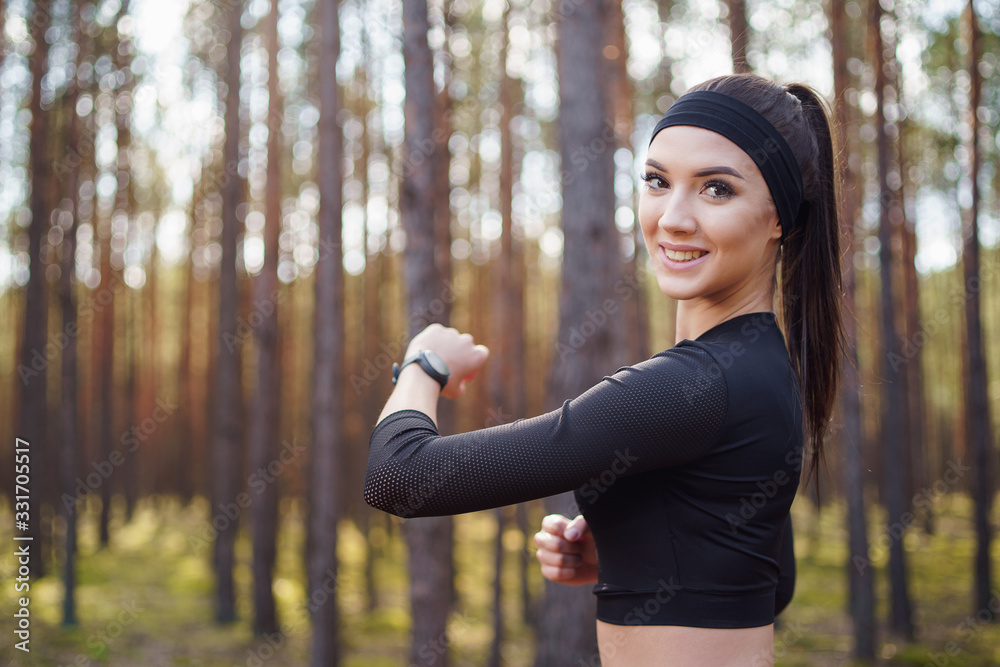 Woman running in the woods checking smartwatch. Natural light in forest. Woman running in the woods checking smartwatch. Natural light in forest.