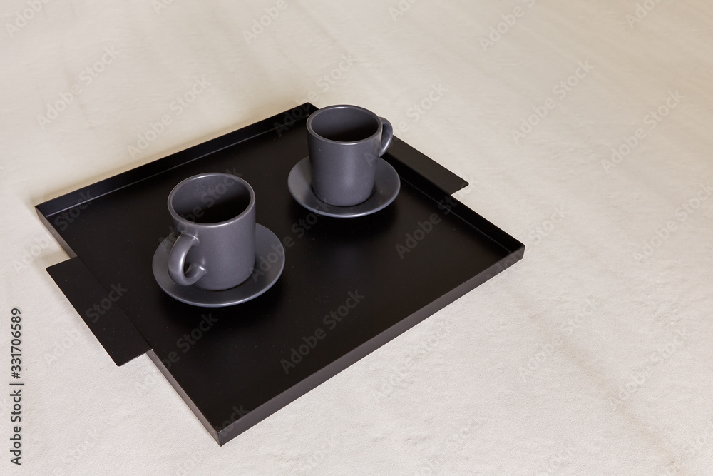 two black cups stand on a tray two black cups stand on a tray