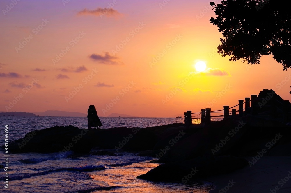 Young couple admires beautiful sunset by the sea