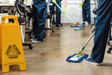 cropped view of team of young cleaners washing floor with mops in office