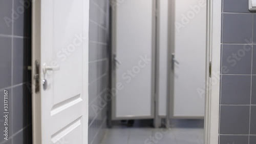 A woman with urinary incontinence in public restroom runs in toilet cabin. Finally a woman going out from cabin