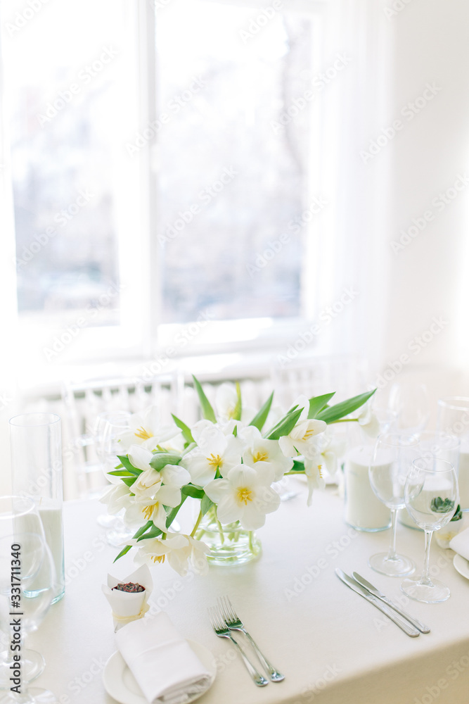  Light decor in the style of fine art. Glasses and tulips in the composition. Wedding table decor with white Studio.