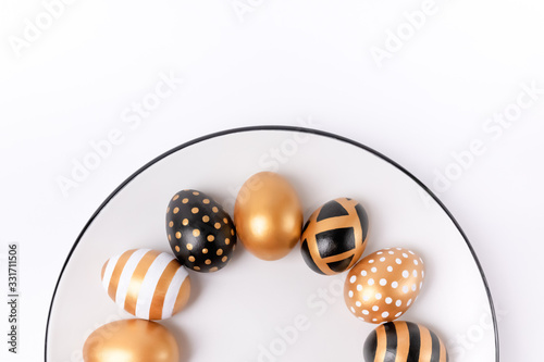 Stylish Easter golden decorated eggs on white plate isolated on white background. Trendy flat lay easter. Plate with easter eggs trendy colored. Copy space. Minimal style easter. Flat lay, top view