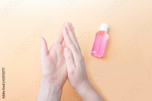 Disinfection of female hands with sanitizer gel against virus and bacteria on orange background. Coronavirus protection and healthcare concept. Safety rules during quarantine. Copy space for text