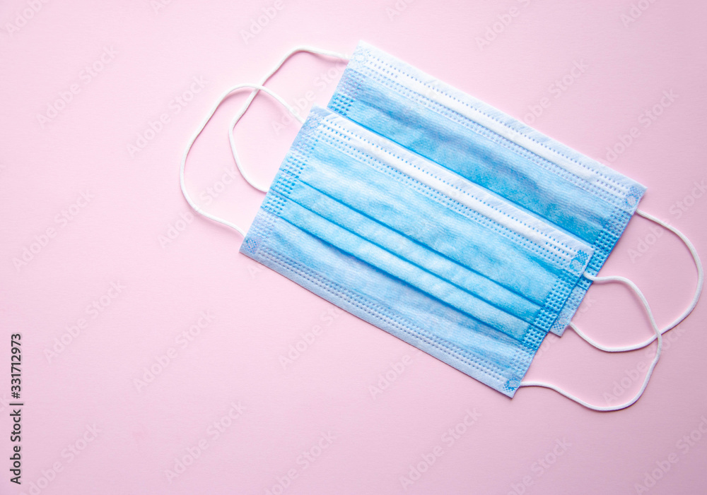 Fototapeta premium Two blue medical masks lie on a yellow, blue and pink background. Place for text. Copy Space. COVID-19