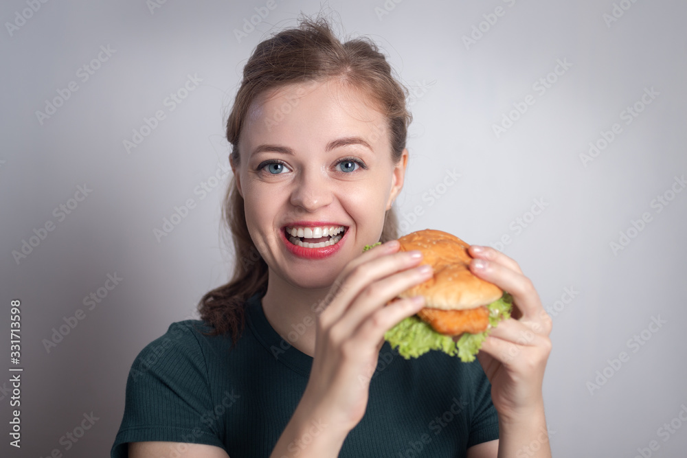 Smiling young Caucasian woman girl holding eating chicken burger