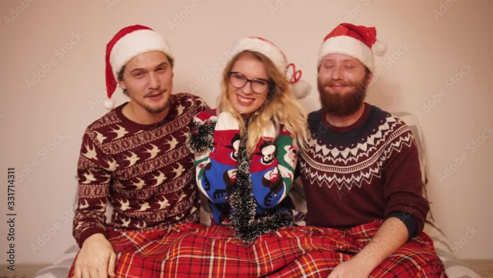 Three smiling teenagers in Christmas clothes and hats dance to music in slow motion Three smiling teenagers in Christmas clothes and hats dance to music in slow motion