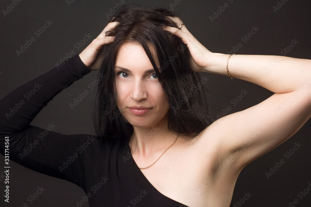 portrait of a brunette on a dark gray studio background in a black dress