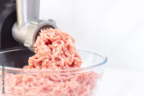 Closeup of minced meat exiting from a grinder. Healthy homemade stuffing. on a light background