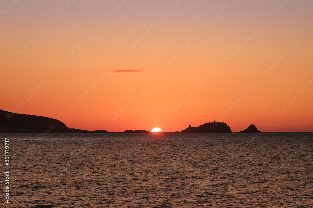 Sun setting behind La Pietra at Ile Rousse in Corsica