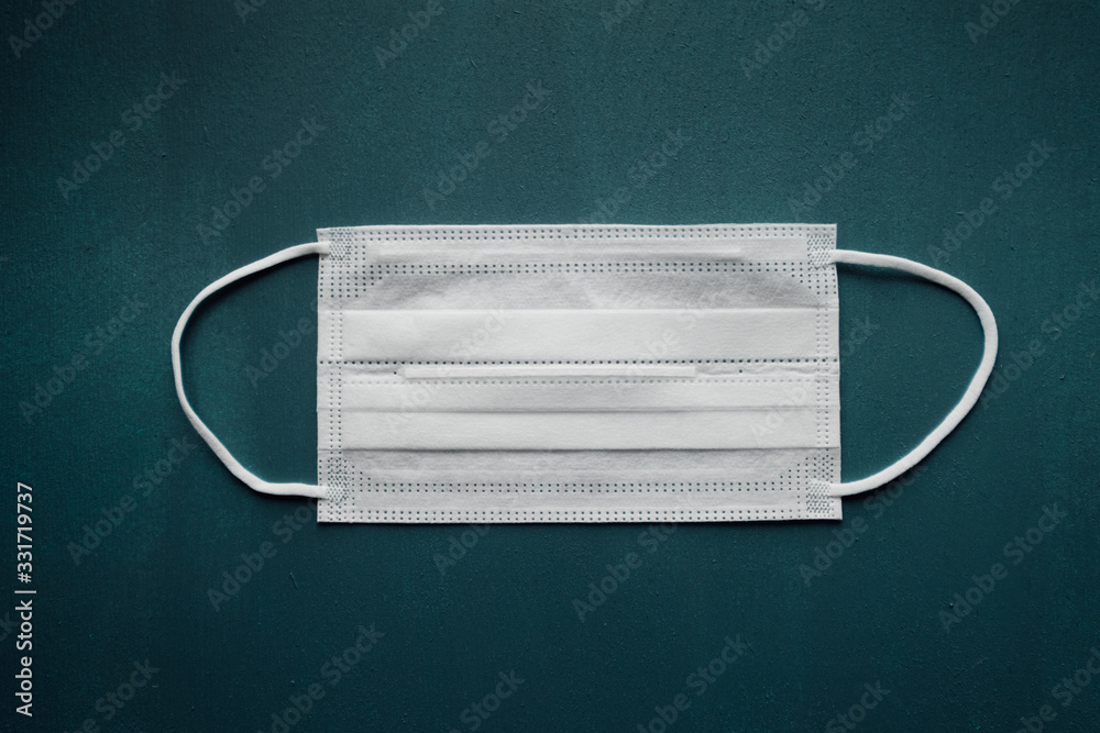 One white medical mask lie on a dark blue wooden background One white medical mask lie on a dark blue wooden background