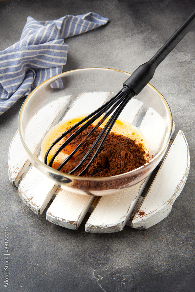 Fototapeta premium Preparation of chocolate dough for sweet pastries (pancakes, cupcakes, brownies), mixing of ingredients (milk, eggs, flour, cocoa)