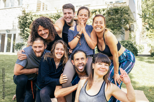 Yoga group smiling at camera. Happy young men and women in sportswear gathering together and smiling at camera in park. Yoga concept