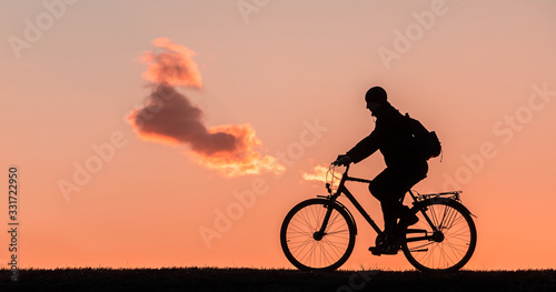 silhouette of a man who rides a bicycle on a sunset background