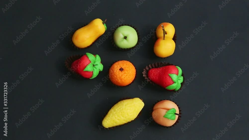 top view closeup hand takes away fruit shaped marzipan candy from assortment top view closeup hand takes away fruit shaped marzipan candy from assortment