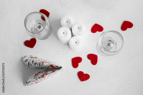 Desk prepared for Valentine's day. Red hearts, candles and glasses of wine.