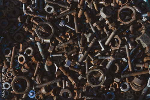 Many old rusty bolts and nuts of various sizes lie on the surface. Toned. Background or wallpaper.