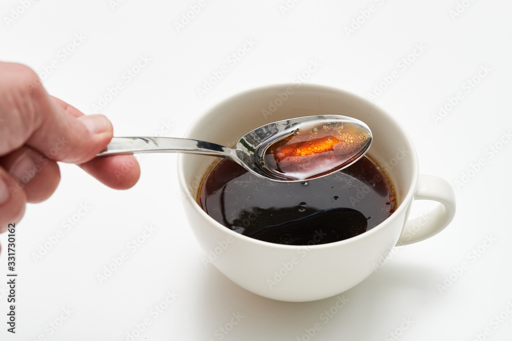 White cup of black bullet proof coffee with healthy oil on white table White cup of black bullet proof coffee with healthy oil on white table