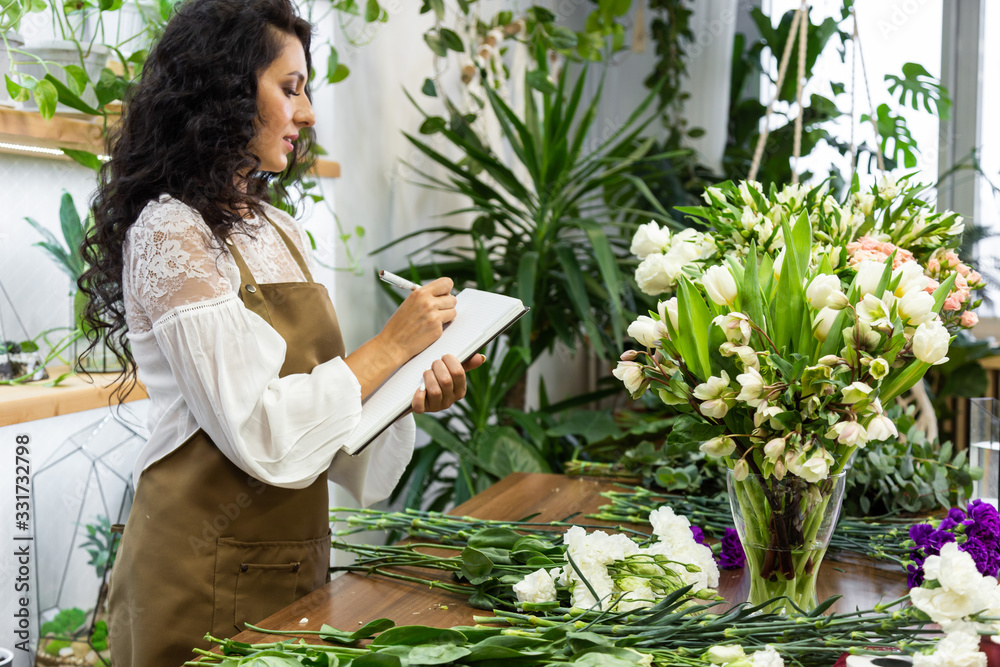 Attractive young woman florist is working in a flower shop. Attractive young woman florist is working in a flower shop.