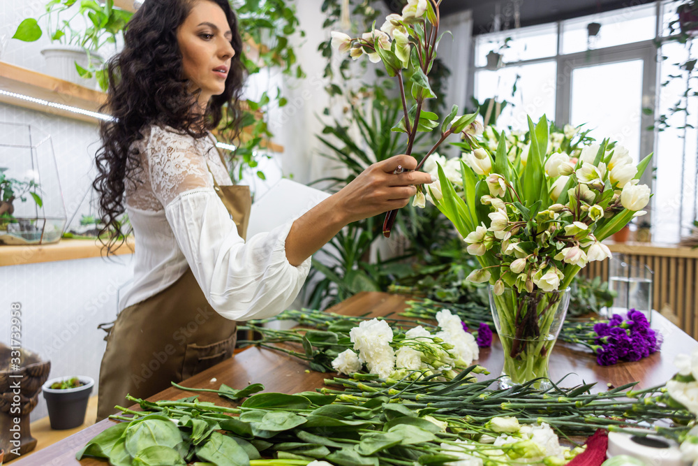Obraz premium Attractive young woman florist is working in a flower shop.