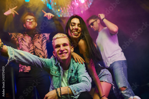 Going crazy and posing for the camera together. Young people is having fun in night club with colorful laser lights
