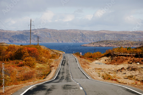 Asphalt road to Teriberka in the Northern tundra landscape of the Kola Peninsula. Natural landscapes in the autumn season. Murmansk Region, Russia photo